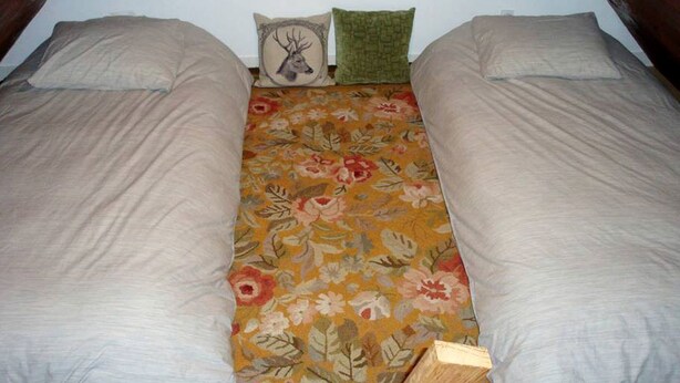 Una cama con ropa de cama floral y dos almohadas, una con un diseño de ciervo.