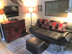 A living room with a sofa, a television, a lamp, and a decorative cabinet.