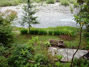 A river with a wooden structure in the foreground, surrounded by dense greenery.