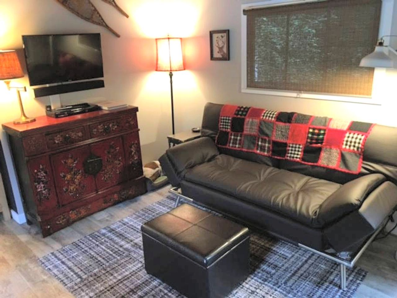 A living room with a sofa, a television, a lamp, and a decorative cabinet.