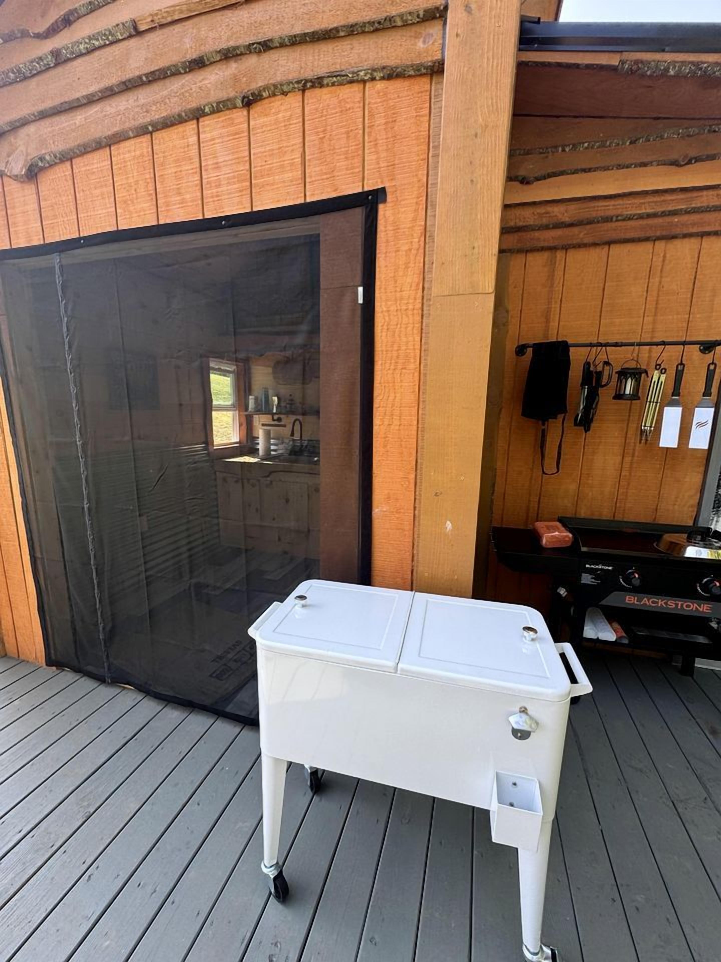 A white portable grill on a wooden deck with a sliding glass door and a black grill in the background.