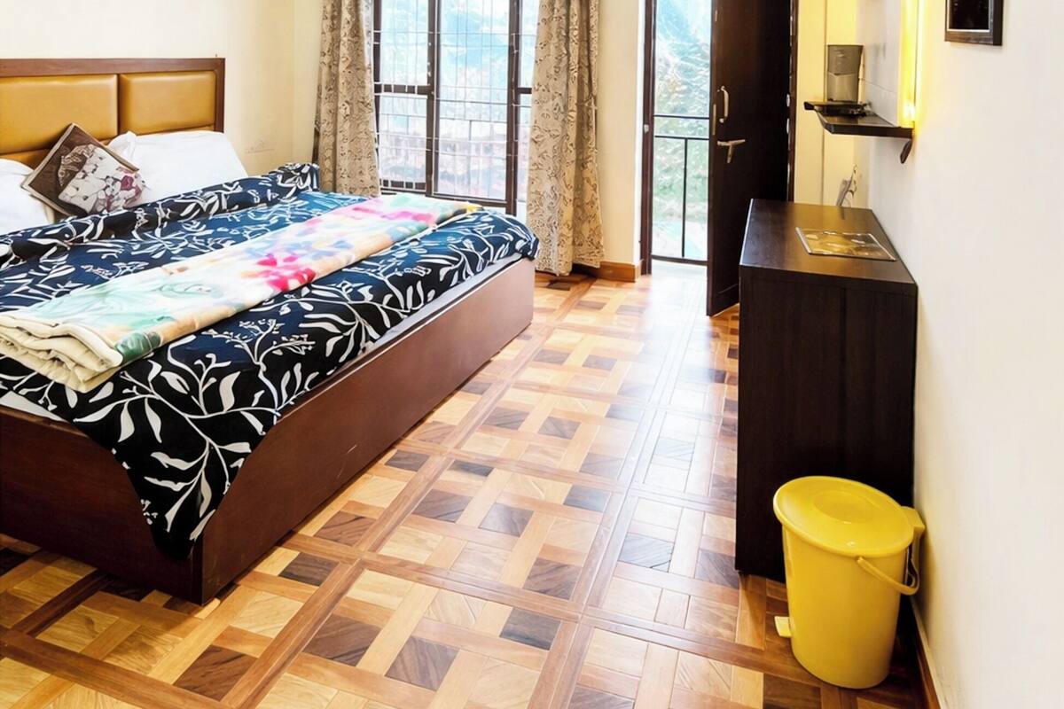 Une chambre à coucher avec un lit, un plancher en bois, une porte, une fenêtre et une étagère fixée au mur.
