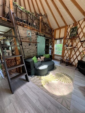 Un interior acogedor con una cama en altillo, un sofá, una escalera y un muro decorativo.