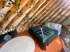 Ein Schlafzimmer im Dachgeschoss mit einem Bett, einem weißen Teppich und Holzbalken.