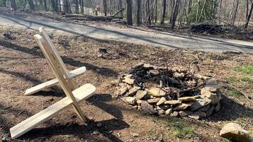 Une chaise en bois et un foyer en pierre, situés dans une zone boisée.