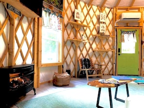 Una habitación acogedora con chimenea, una puerta verde y un muro de celosía con cuadros.