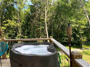 Un jacuzzi en una terraza de madera con vista a un bosque.