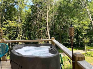 Ein Whirlpool auf einer Holzterrasse mit Blick auf einen Wald.