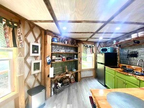 Une cuisine de taille réduite, équipée d’un réfrigérateur, d’un évier et d’étagères en bois.