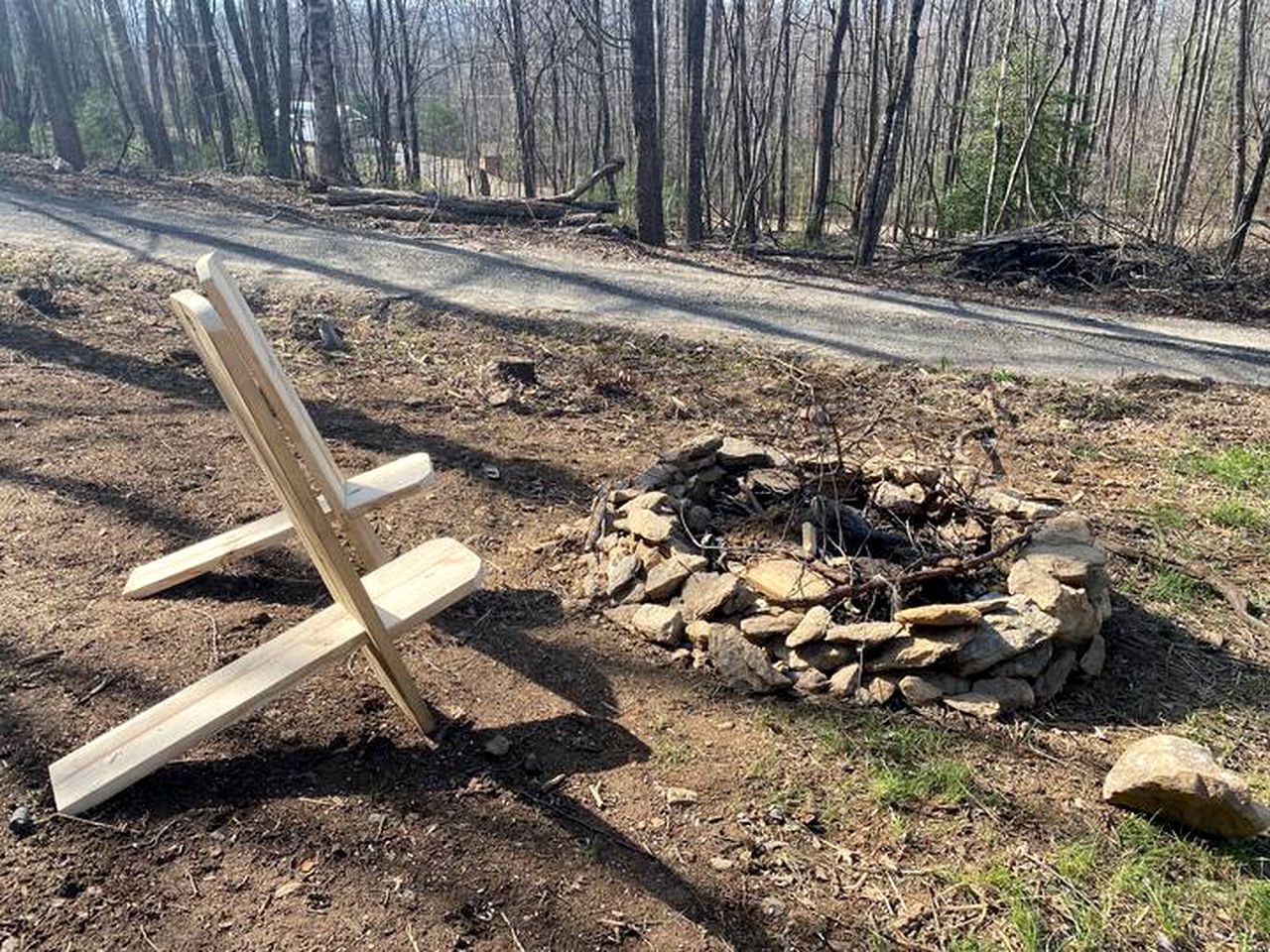 Une chaise en bois et un foyer en pierre, situés dans une zone boisée.