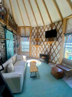 A cozy interior with a sofa, a wooden coffee table, a fireplace, and a TV mounted on a lattice wall.