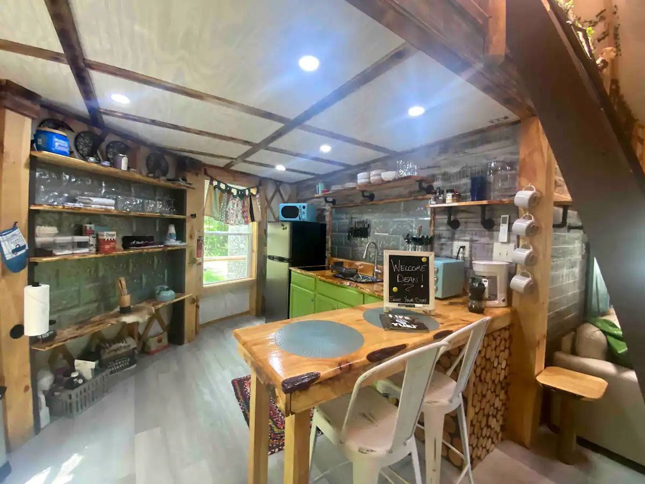 A compact kitchen with wooden cabinets, a dining table, and a microwave.