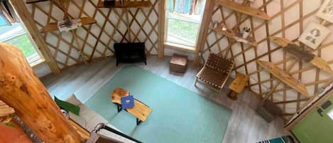 A rustic interior with a wooden lattice wall, a flat-screen TV, a small table, and a bench.