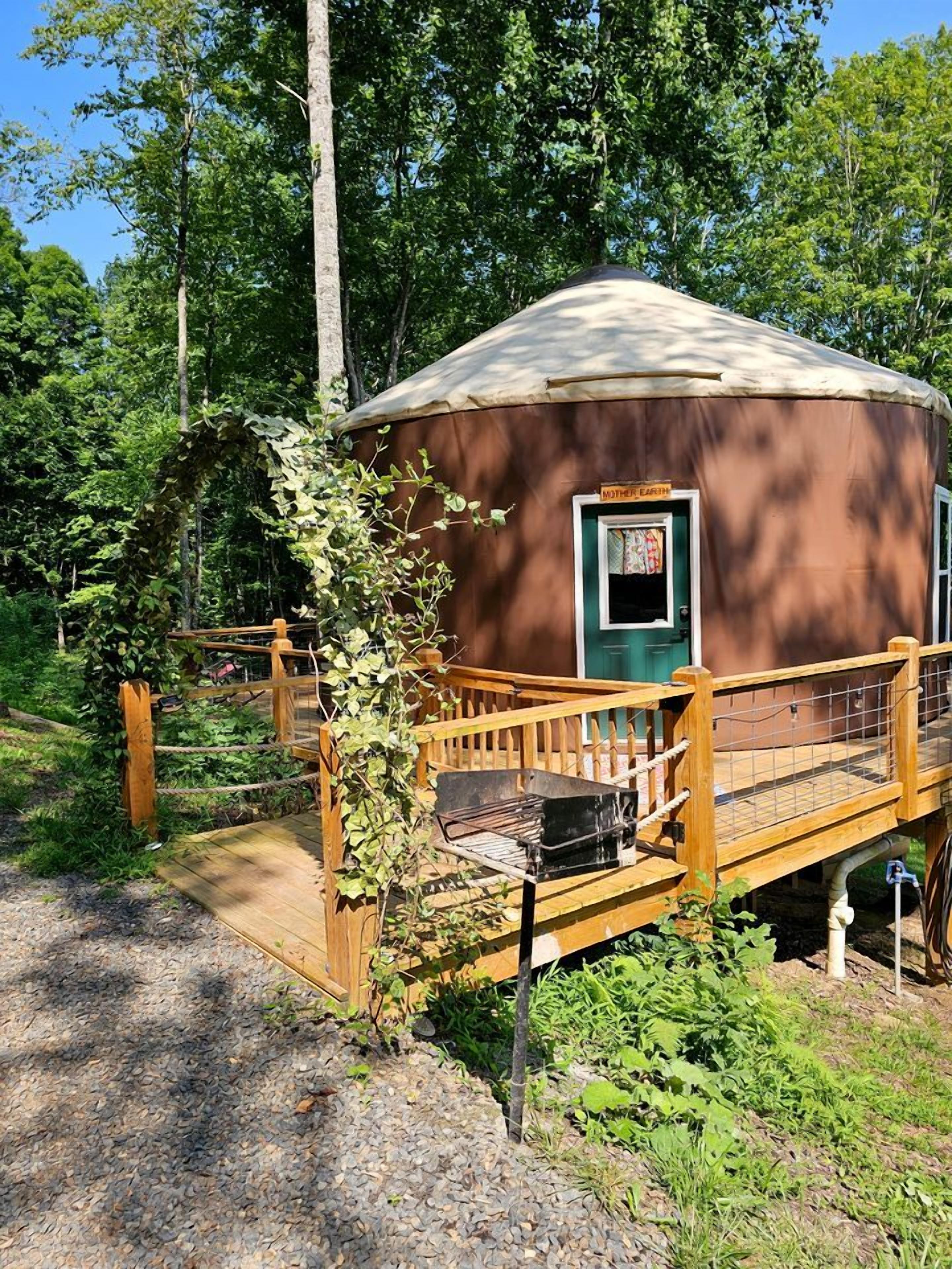 A yurt with a wooden deck, a door, and a window.