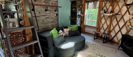 A cozy interior with a loft bed, a sofa, a ladder, and a decorative wall.