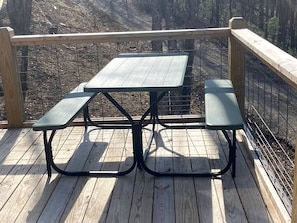 Ein Picknicktisch mit Bänken auf einer Holzterrasse mit Metallgeländer.