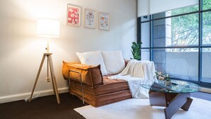Een moderne kamer met een bank, een glazen salontafel, een lamp en lijstwerken aan de muur.