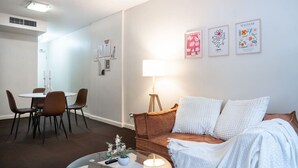 Een moderne woonkamer met een ronde eettafel, een bruine leren bank en een lamp.