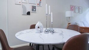 Een ronde marmeren tafel met een witte vaas en drie kandelaars, omringd door bruine stoelen.