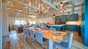 Eine geräumige Küche mit Holzbalken, ein Essbereich mit Holztisch und -stühlen und Blick zum Wohnzimmer.
