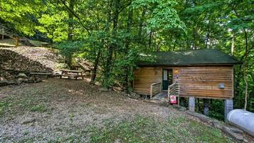 A rustic cabin with a wooden exterior, a small porch, and a picnic table nearby.