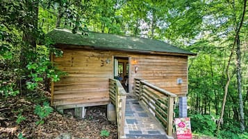 A wooden cabin with a porch, a staircase, and a welcome sign.
