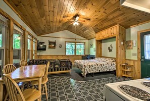 Un interior de cabaña con comedor, sofá, cama y cocina.