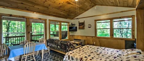 Une cabine comprenant un coin repas, un canapé, un lit et de grandes fenêtres.