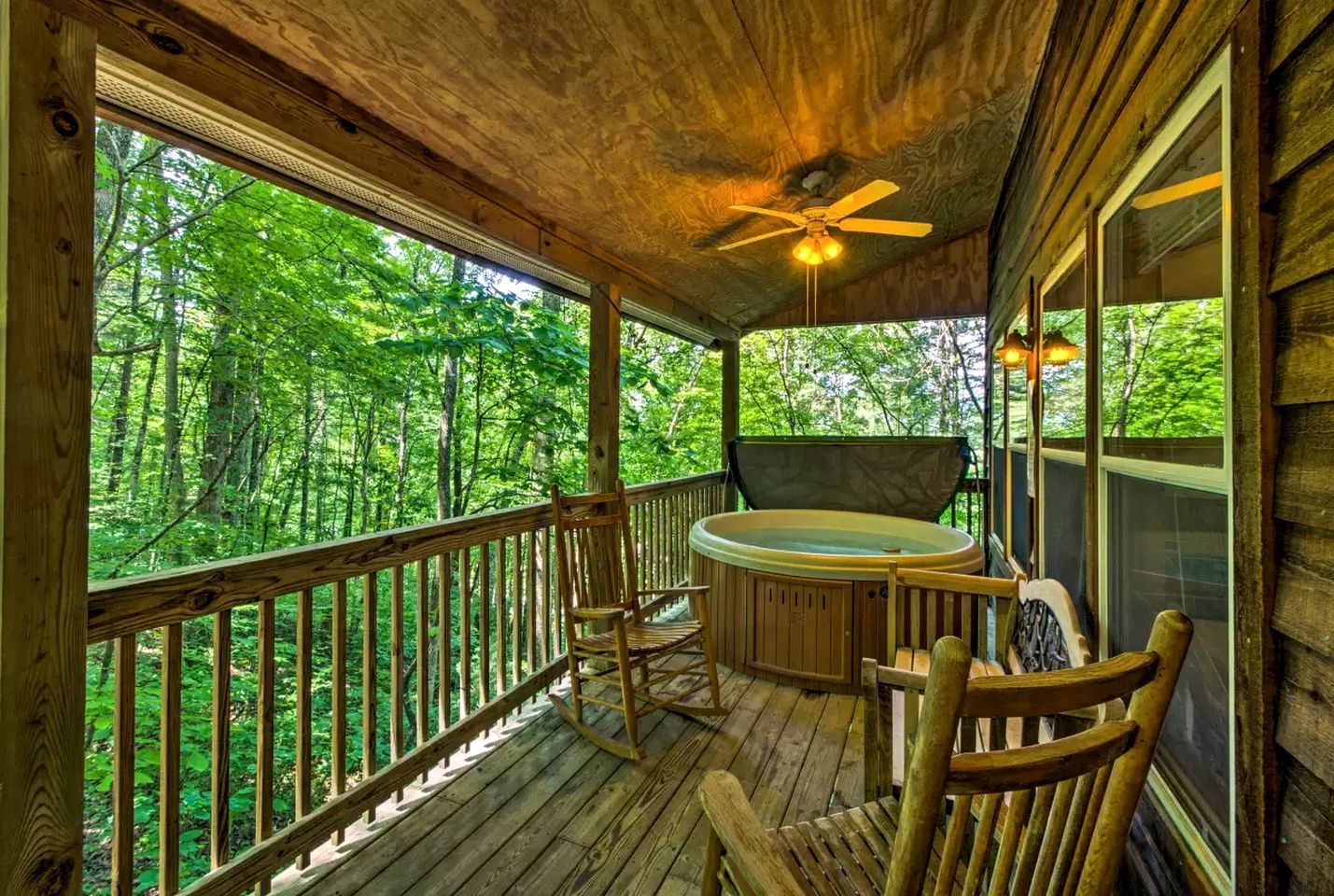 Um deck de madeira com hidromassagem, cadeiras e ventilador de teto.