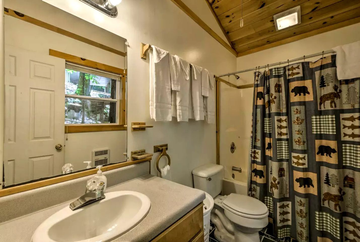 A bathroom with a sink, toilet, and shower curtain with animal prints.