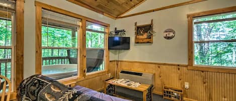 L’intérieur d’une cabane est doté d’un plafond en bois, de grandes fenêtres, d’un téléviseur, d’une cheminée et d’un coin salon confortable.