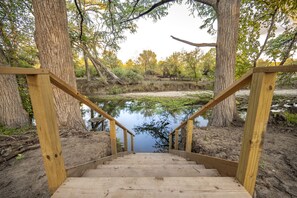 Una escalera de madera que lleva a un estanque rodeado de árboles.