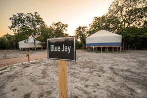En skylt med texten ”Blue Jay” på en campingplats med tält och träd.