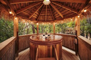 Ein hölzernes Gazebo mit einem runden Tisch, einer Weinflasche und einem Weinglas darauf.