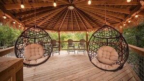A wooden deck with hanging chairs and a thatched roof.