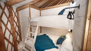 A bunk bed with a ladder, a white headboard, and a blue blanket.