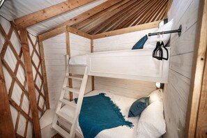A bunk bed with a ladder, a white headboard, and a blue blanket. - Enchanting Glamping Yurt with Access to the Tranquil Medina River in Bandera, Texas (Bandera)