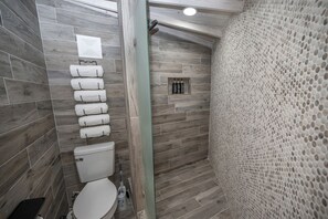 A bathroom with a wooden floor, a toilet, a shower area, and a towel rack. - Enchanting Glamping Yurt with Access to the Tranquil Medina River in Bandera, Texas (Bandera)