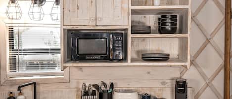 Een compact keuken met een Galanz magnetron, zwarte borden, een Keurig koffiezetapparaat en een spoelbak met afwasmiddel.