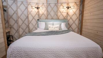 A bed with a quilted white cover, a headboard with a light blue top, and two wall-mounted light fixtures.