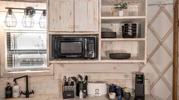 A compact kitchen with a Galanz microwave, black plates, a Keurig coffee maker, and a sink with dish soap.