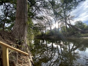 Un área boscosa tranquila con una plataforma de madera que da vista a una masa de agua serena.
