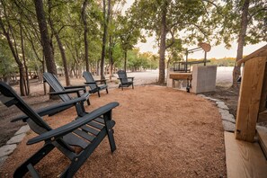 An outdoor seating area with Adirondack chairs, a fire pit, and a wooden deck.