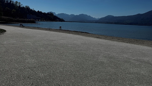 Ein gepflasterter Bereich mit einem See und Bergen im Hintergrund.