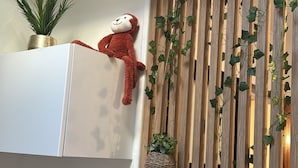 Ein Zimmer mit einer Wand aus Holzlatten, einem weißen Heizkörper, einem Regal mit einer Pflanze und einem Stofftier.