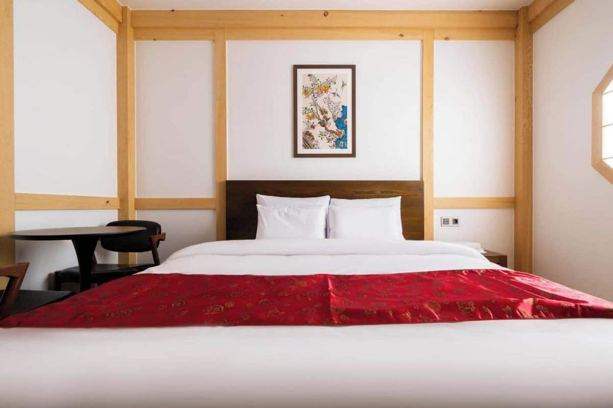 Una habitación de hotel con una cama, una mesita y una silla.