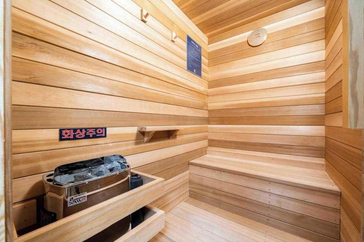 Una sauna con paredes y bancos de madera, un calentador y un letrero que indica la zona de sauna.