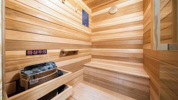 A sauna with wooden walls and benches, a heater, and a sign indicating the sauna area.