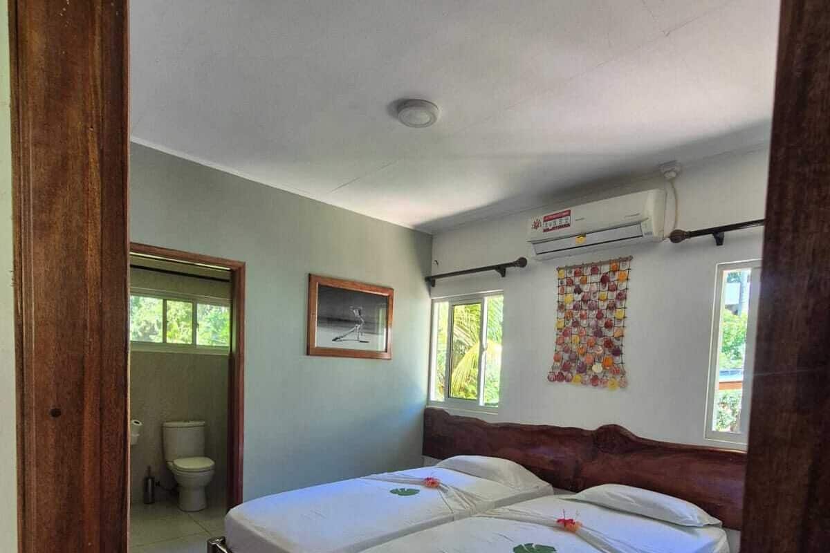 A room with two beds, a window, a picture on the wall, and a ceiling fan.
