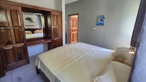 A bedroom with a bed, wooden wardrobe, and a painting on the wall. - Fond B'offay Lodge (Praslin Island)